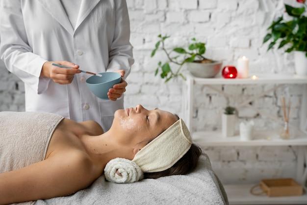 A woman receiving a facial treatment from a skincare professional in a serene spa setting.