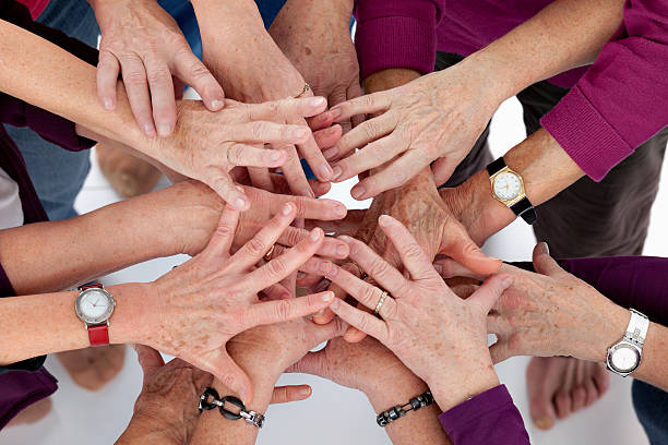 Group of elderly people joining hands together in unity